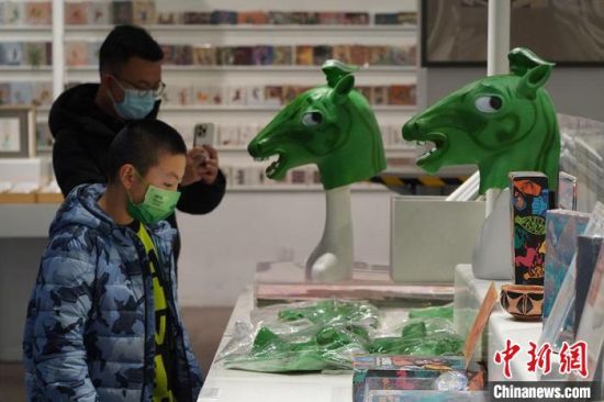 圖為“神馬來(lái)了”銅奔馬頭套吸引參觀者駐足?！【琶赖┰?攝