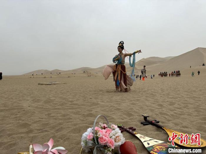 圖為2023年4月底，敦煌大漠“逐舞者”奧楠在鳴沙山月牙泉景區(qū)視頻直播敦煌舞?！●T志軍 攝