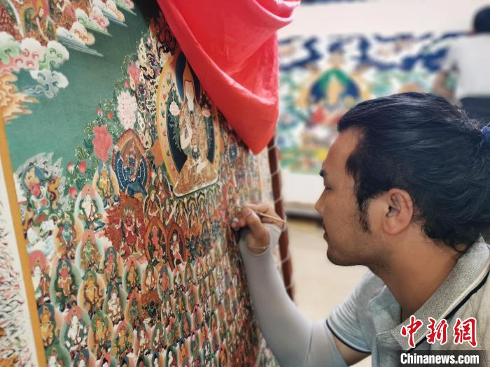 圖為更登才讓的徒弟繪畫唐卡?！?zhí)砀?攝
