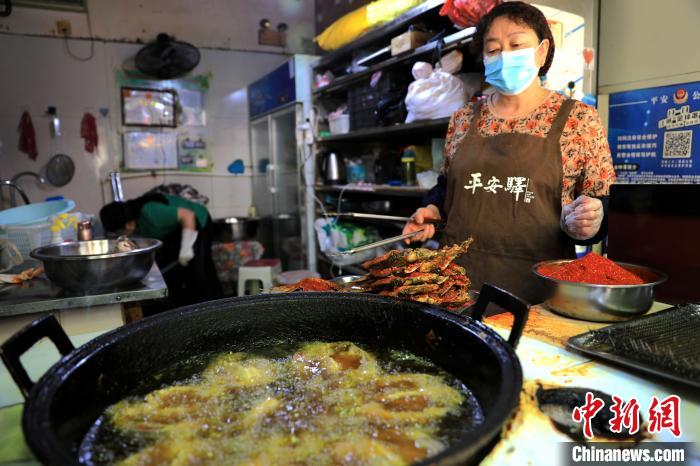 圖為平安驛·河湟民俗文化體驗地內(nèi)的商戶炸干板魚?！⊙Φ?攝